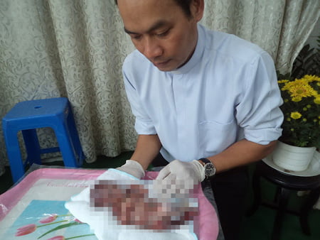 Linh mục Nguyễn Văn Tịch đang tắm rửa cho một thai nhi.